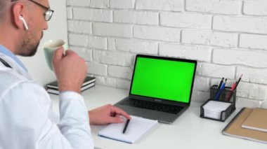 Yeşil ekran dizüstü bilgisayar konsepti: Tıp çalışanı kahve içen hastayı dinliyor