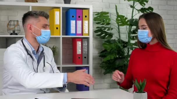 Doctor and patient in protective masks shake hands after agreeing on treatment — Stock Video