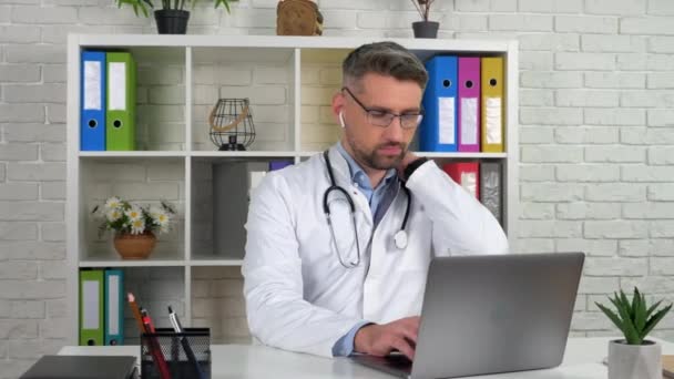 Втомився лікар масаж шиї натирає напружені м'язи після тривалої роботи на ноутбуці — стокове відео