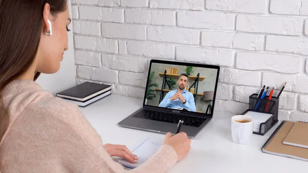 Evde çalışan kadın öğrenci videosu. Bilgisayarı ara. Not defterine yazıyor.