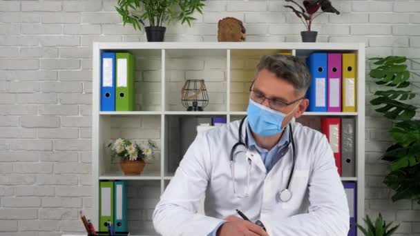 Dokter berbicara mendengarkan pasien di kantor rumah sakit, menulis gejala-gejala di notebook — Stok Video