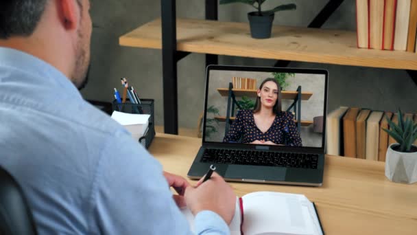 Człowiek student studiuje online przez konferencję wideo rozmowy laptop, pisze w notebooku — Wideo stockowe