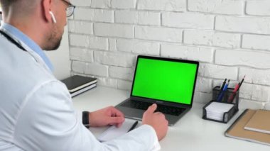 Doktor görünümlü yeşil ekran dizüstü bilgisayar danışma konuşma hastası tedavi seçenekleri sunuyor