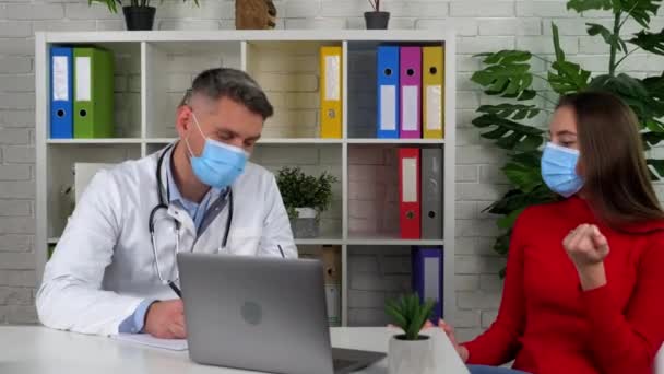 Doctor and patient wears protective masks on faces in hospital communicates talk — Stock Video