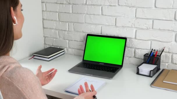 Улыбающаяся студентка дома слушает учителя с ноутбуком с зеленым экраном — стоковое видео