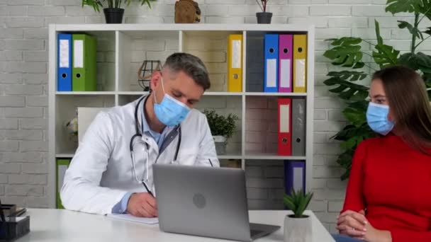 Trabalhador médico em conversa casaco branco ouvir cliente escreve sintomas no caderno — Vídeo de Stock