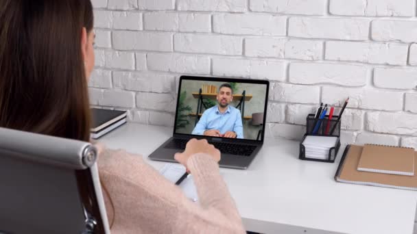 Frau lernen zu Hause Online-Videoanruf Laptop, schreibt in Notizbuch hören Lehrer — Stockvideo