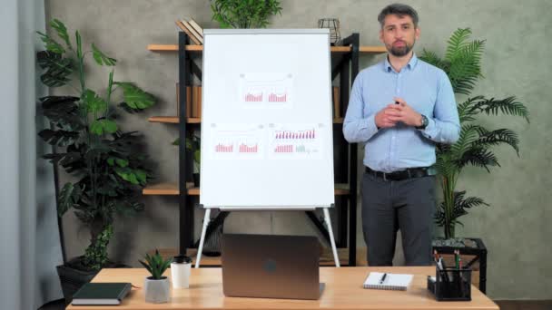 Guru Man berdiri di dekat flip chart greets berbicara siswa remote video call chat — Stok Video