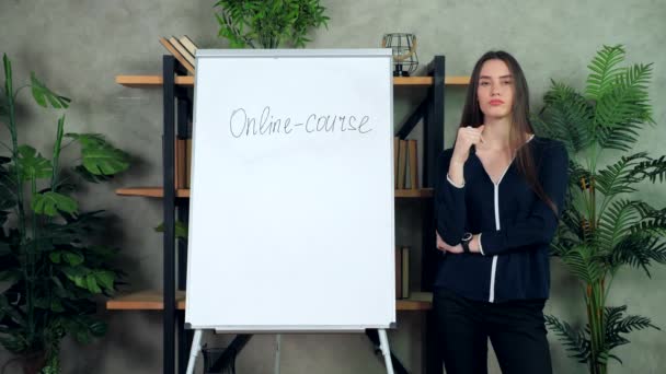 Bedachtzame vrouw business coach staat in de buurt whiteboard op zoek camera luistert — Stockvideo