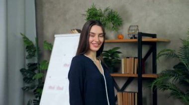 Gülümseyen kadın iş koçu arka plandaki kameraya bakar.