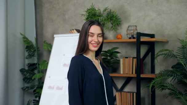 Smiling woman business coach turns head looking camera on background whiteboard — Stock Video