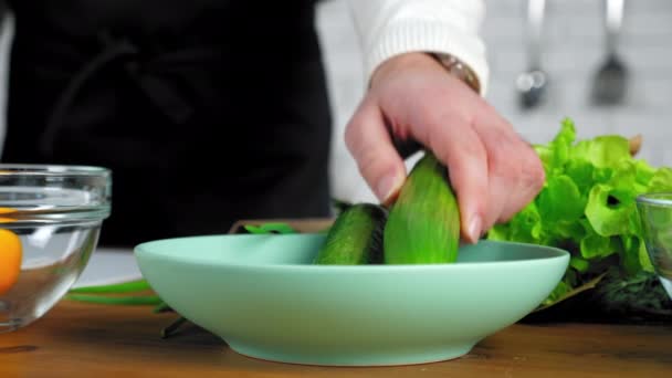 Primer plano manos hombre chef poner pepinos de alimentos frescos en el plato en la cocina casera — Vídeos de Stock