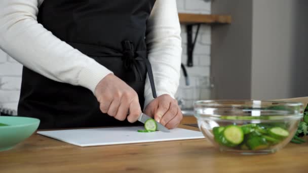 Cocinero profesional hombre en delantal negro en rodajas de pepino fresco en la cocina casera — Vídeos de Stock