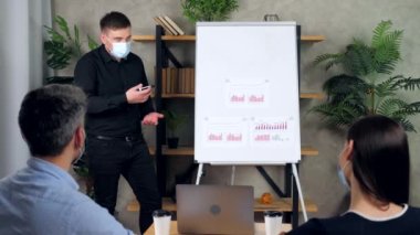 Korumacı tıbbi maskeli bir adam ve bir kadın grafik çizelgesini dinliyor.