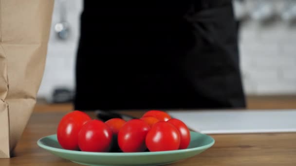 Primer plano manos hombre chef en delantal negro poner comida fresca tomate rojo cereza en el plato — Vídeos de Stock