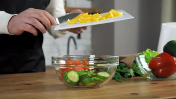 Kéz szakács dobja kés apróra vágott harang paprika vágódeszka saláta tál a konyhában — Stock videók