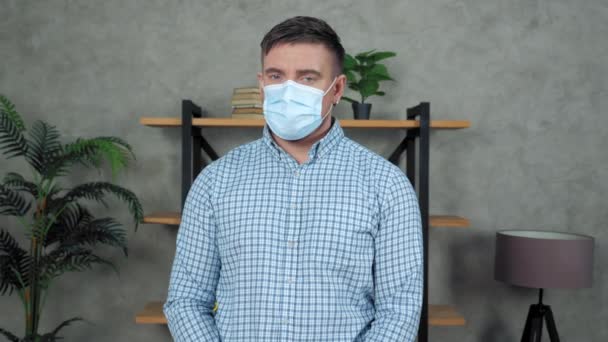 Грустный бизнесмен носит защитную медицинскую маску на лице поворачивает голову, глядя в камеру — стоковое видео