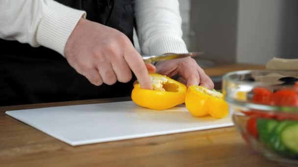 Χέρια σεφ άνθρωπος ξεφλούδισμα φρέσκο κίτρινο bell pepper στην κοπή του σκάφους στην κουζίνα στο σπίτι — Αρχείο Βίντεο