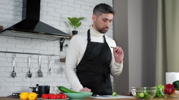 Man chef élelmiszer tanár szeletelt uborka a konyhában tanít online videókamera — Stock videók