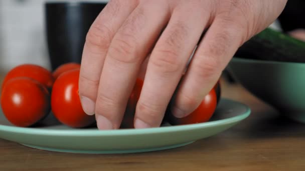 Κοντινό χέρι σεφ άνθρωπος παίρνει φρέσκο τομάτα κεράσι από μπολ με τραπέζι κουζίνας — Αρχείο Βίντεο