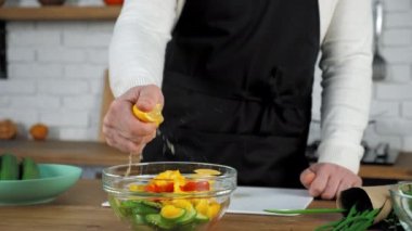 El şefi salataya yarım taze limon sıkıştırıyor ve cam kasede sebze yiyor.