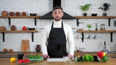 Önlüklü adam ev hanımlarına salata pişirmek için malzeme göstermeyi öğretiyor.