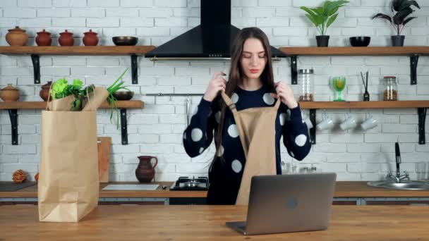 Γυναίκα έρχεται στην κουζίνα βάζει ποδιά προετοιμάσει μελέτη σε απευθείας σύνδεση μάθημα μαγειρικής στο φορητό υπολογιστή — Αρχείο Βίντεο