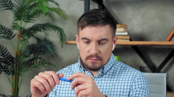 Pengusaha yang bijaksana memakai earphone nirkabel di kantor berpikir masalah solusi — Stok Video