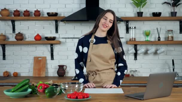 Vrouw geeft online video call laptop, vertelt show komkommer webcam in de keuken — Stockvideo