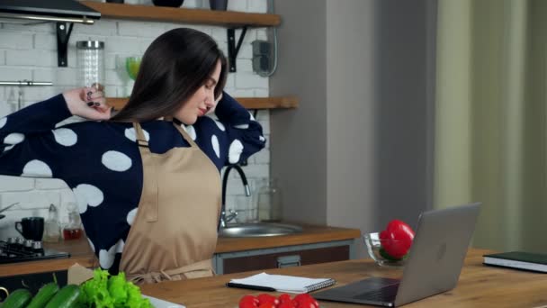 Tired woman writes culinary recipe in notebook massages neck after using laptop — Stock Video