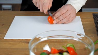 Aşçı aşçı ev mutfağında taze vişneli domates dilimledi.