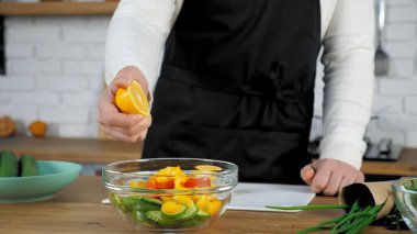 El şefi salataya yarım taze limon sıkıştırıyor ve cam kasede sebze yiyor.