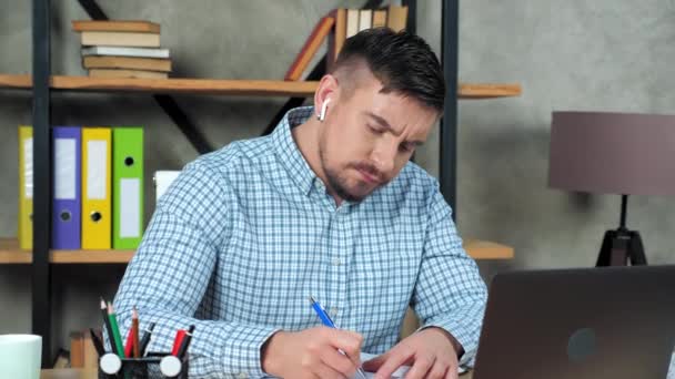 Tired businessman writes in notebook massaging neck after over work at laptop — Stock Video