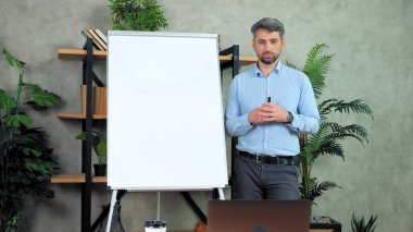 İş adamı koçu beyaz tahtaya yakın duruyor. İnternette görüntülü konuşma öğretiyor.