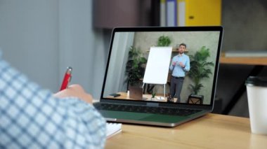 İşadamı deftere yazıyor, online eğitim işletme dersi laptopu okuyor.