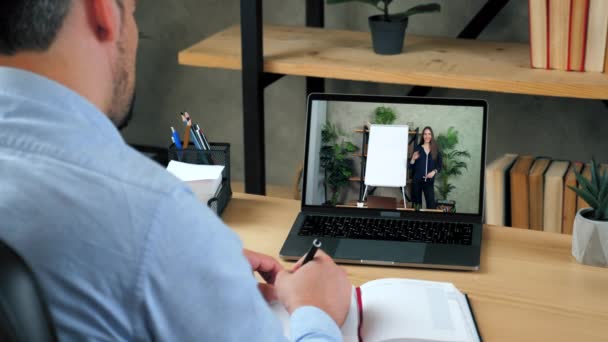 Mann studiert online per Videokonferenz Laptop, schreibt in Notizbuch — Stockvideo