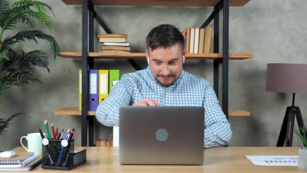 Sorrindo homem sentado na cadeira na mesa em casa escritório aberto e começar a usar laptop — Vídeo de Stock