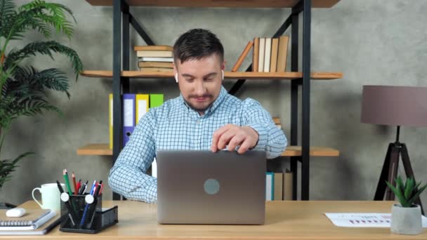 Lächelnder Student sitzt auf Stuhl am Schreibtisch zu Hause offen und beginnt mit Laptop — Stockvideo