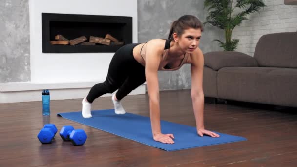 Atletisk kvinna i sportkläder gör fitness aerobic motion hemma i sovrummet — Stockvideo