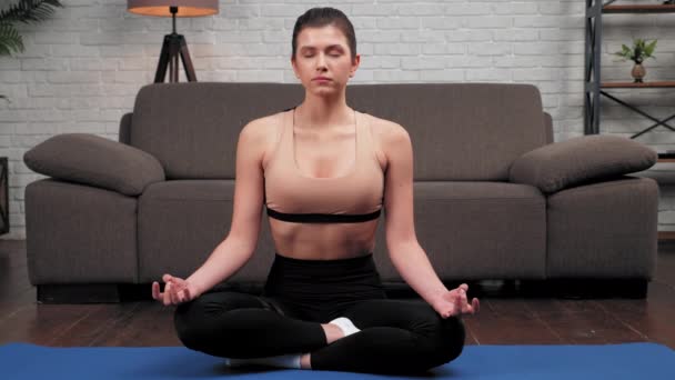 Закрыть спокойную спортивную женщину в спортивной одежде практикует йогу дома в спальне — стоковое видео