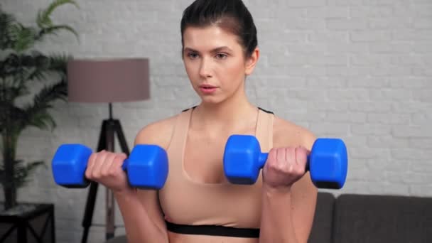 Femme athlétique faisant des boucles biceps avec haltères, entraînement à la maison dans la chambre — Video