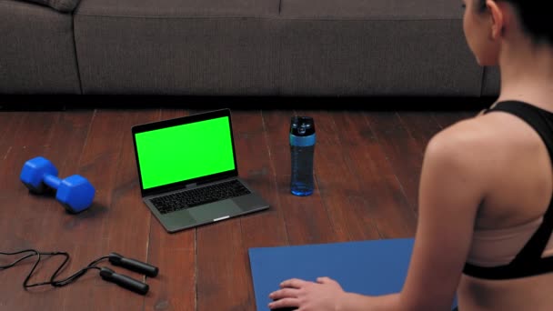 Concepto de computadora portátil de pantalla verde: La mujer se sienta en la estera de yoga, ver el deporte curso en línea — Vídeos de Stock