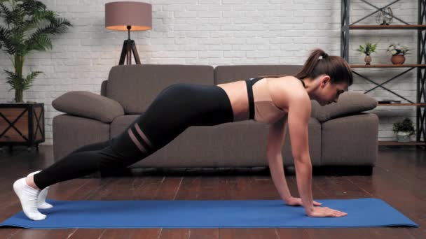 Sterke gespierde sportvrouw training thuis in de woonkamer op de bank achtergrond — Stockvideo