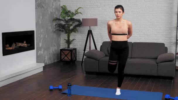 Jonge fitte vrouw in sportkleding doet warming-up voor de training op yoga mat thuis — Stockvideo