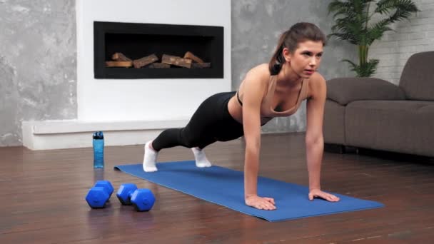 Сильна жінка в спортивному одязі займається тренуванням дошки на фітнес- йога килимок — стокове відео