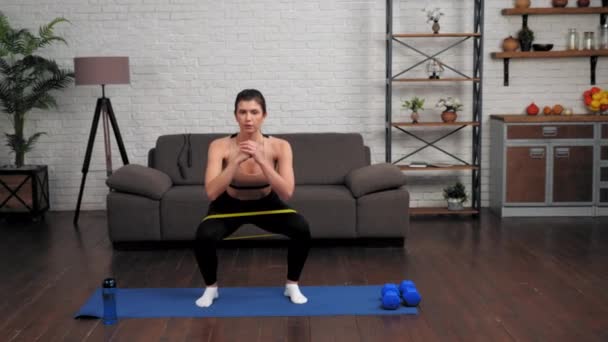 Spor giyim bölümünde formda bir kadın spor antrenmanı yapıyor. Evde yoga minderinde spor yapıyor. — Stok video