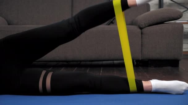 Femme athlétique sportive faisant des exercices de jambes avec bande de boucle sur tapis de fitness — Video