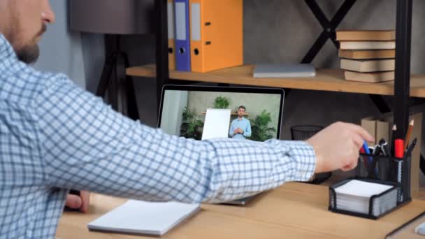 Hombre estudiante estudio en casa oficina en línea videollamada portátil, escribe en el cuaderno — Vídeos de Stock