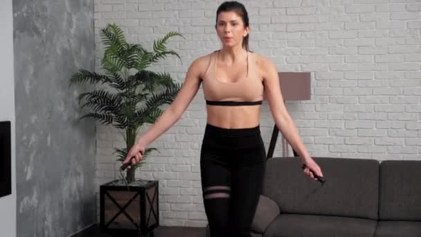 Mulher muscular atlética em sportswear fazendo exercício de corda de salto em casa — Vídeo de Stock