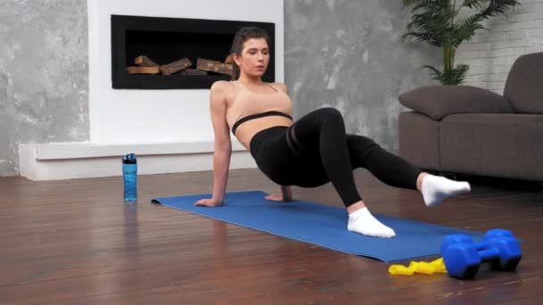 Pasująca kobieta w odzieży sportowej wykonuje trening sportowy na macie fitness jogi w domu — Wideo stockowe